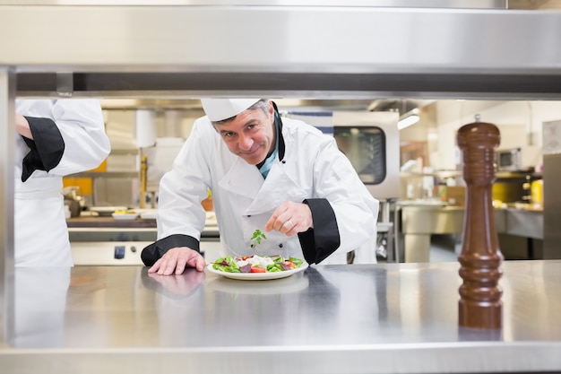 Souriant chef garnir la salade