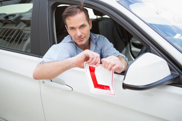 Souriant conducteur déchirer son signe L