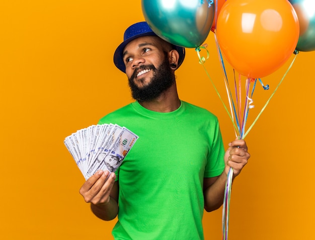 Souriant à côté d'un jeune homme afro-américain portant un chapeau de fête tenant des ballons et de l'argent