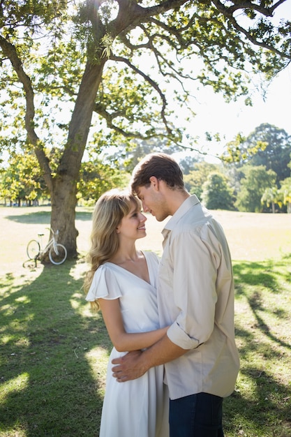 Souriant couple debout et embrassant dans le parc