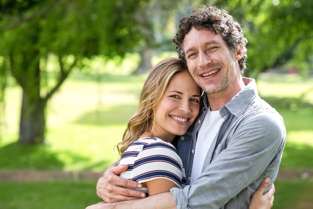 Souriant couple embrassant dans le parc