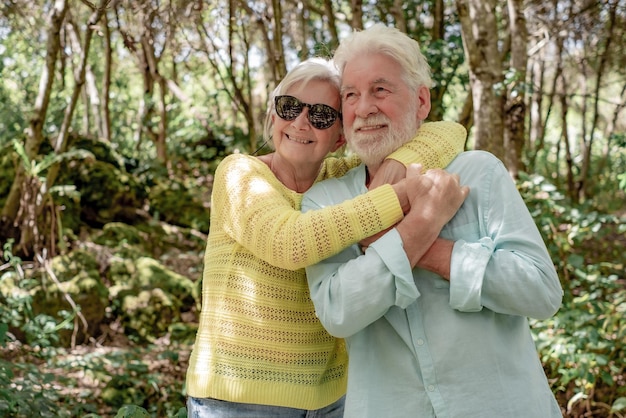 Souriant couple de famille senior étreignant profitant d'une randonnée en montagne dans les bois appréciant la nature