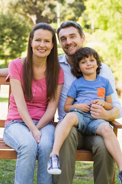 Souriant couple avec fils assis sur un banc de parc