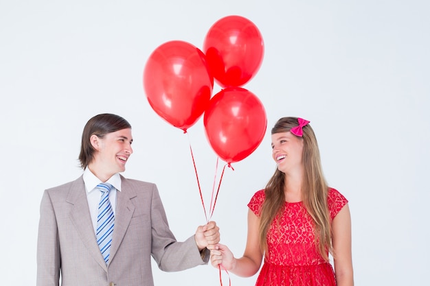 Souriant couple geek tenant des ballons rouges