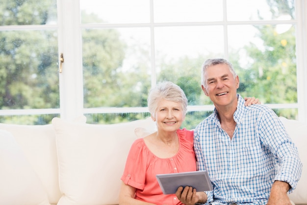 Souriant Couple De Personnes âgées à L'aide D'une Tablette Sur Le Canapé