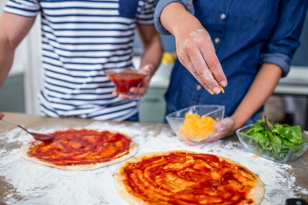 Photo souriant couple prépare une pizza dans la cuisine