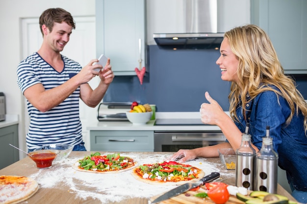 Souriant couple prépare une pizza dans la cuisine