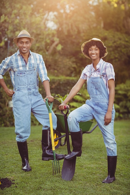 Souriant couple tenant la pelle et le râteau dans le jardin