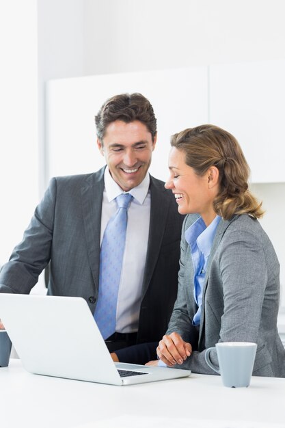 Souriant couple utilisant un ordinateur portable avant le travail