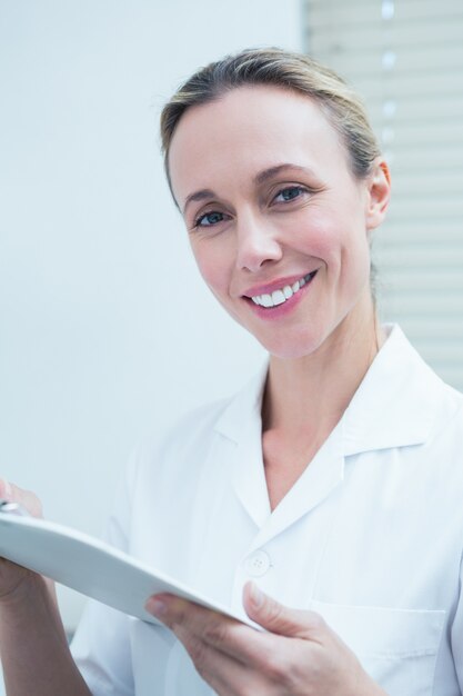 Souriant dentiste femme tenant le presse-papiers