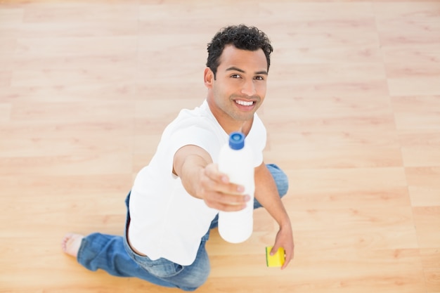 Souriant détergent jeune homme assis sur le sol