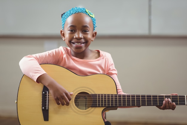 Souriant élève jouant de la guitare dans une salle de classe