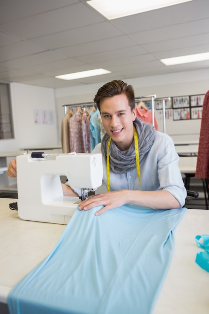 Souriant étudiant à l&#39;aide de la machine à coudre