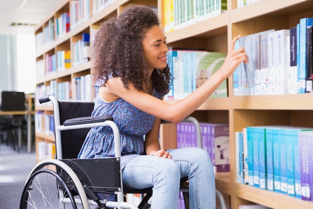 Souriant étudiant handicapé dans un livre de bibliothèque à l&#39;université