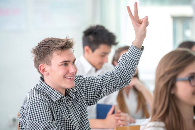 Souriant étudiant levant la main