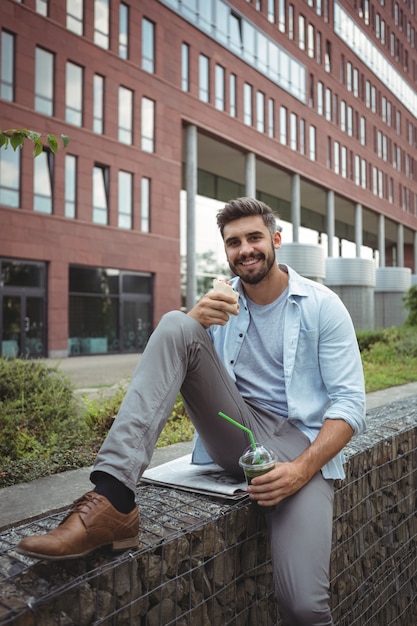 Souriant exécutif ayant rouleau de légumes et jus