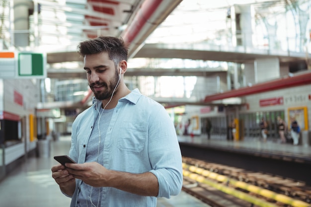 Souriant exécutif écoutant de la musique tout en utilisant un téléphone mobile