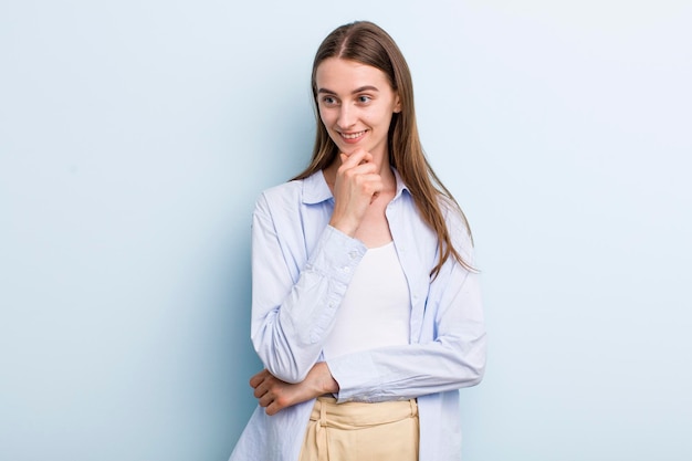 Souriant avec une expression heureuse et confiante avec la main sur le menton se demandant et regardant sur le côté