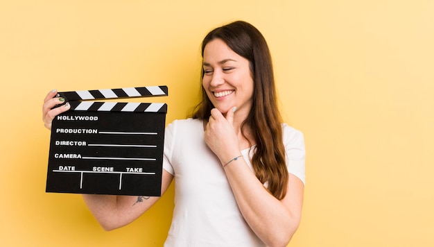 Souriant avec une expression heureuse et confiante avec la main sur le menton