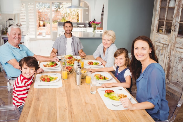 Photo souriant famille avec les grands-parents assis à la table à manger