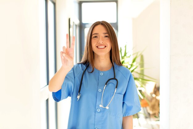 souriant et femme à l'air sympathique, montrant le numéro deux ou la seconde avec la main vers l'avant, compte à rebours