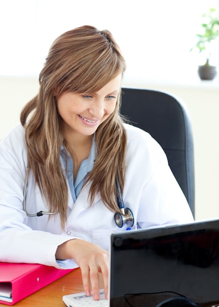 Souriant, femme médecin travaillant avec un ordinateur portable