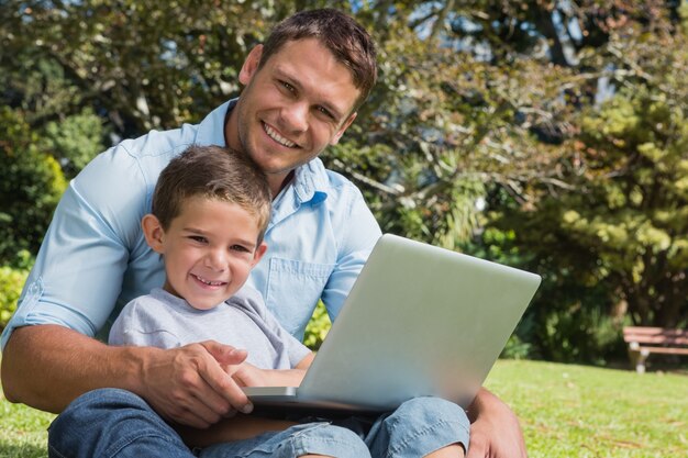 Souriant fils et papa avec un ordinateur portable