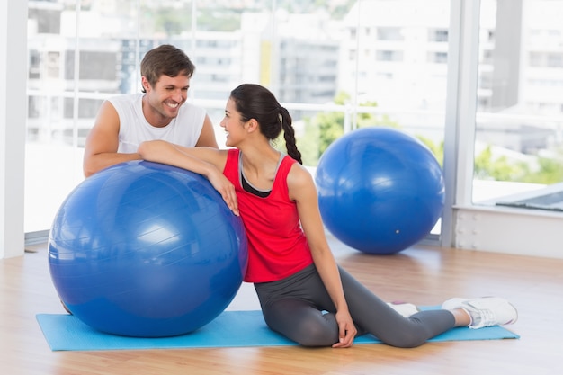 Souriant fit jeune couple avec ballon d&#39;exercice au gymnase