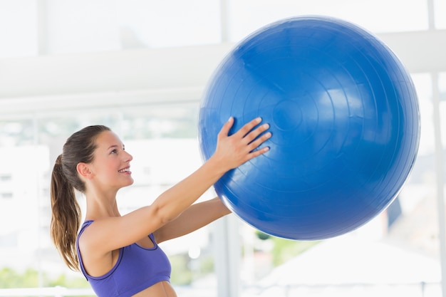 Souriant forme jeune femme tenant un ballon de fitness