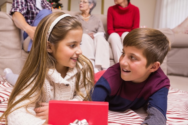 Souriant frère et soeur couché et cadeau d&#39;ouverture