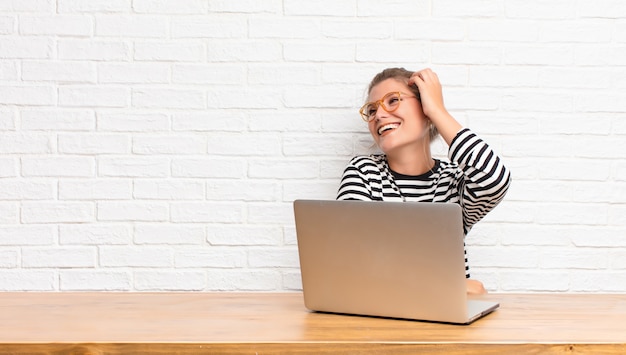 souriant gaiement et avec désinvolture, prenant la main à la tête avec un regard positif, heureux et confiant