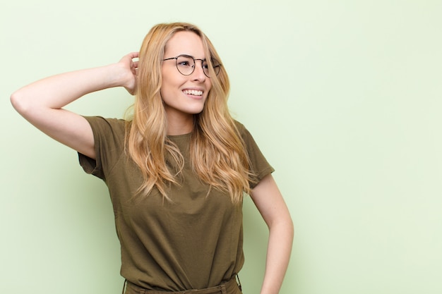 souriant gaiement et avec désinvolture, prenant la main à la tête avec un regard positif, heureux et confiant