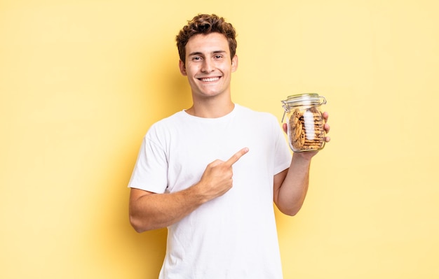 Souriant gaiement, se sentant heureux et pointant vers le côté et vers le haut, montrant l'objet dans l'espace de copie. concept de biscuits faits maison