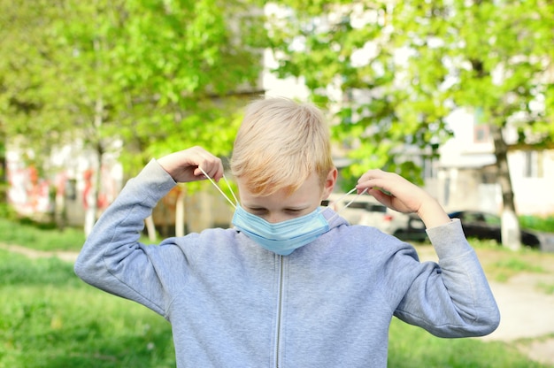 Photo souriant garçon de 9 ans dans la rue a enlevé son masque médical et joue la balle. fin de l'auto-isolement. épidémie de coronavirus.