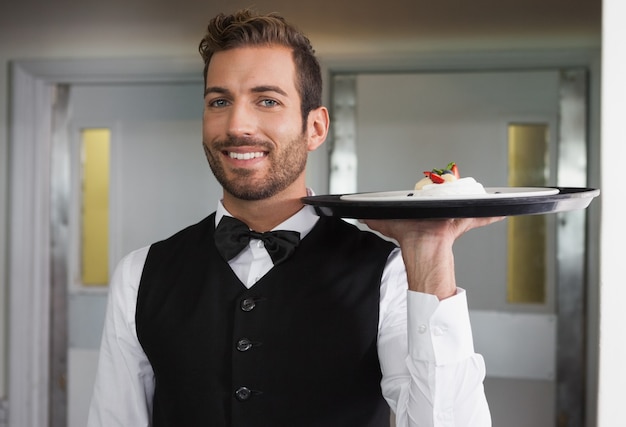 Photo souriant garçon tenant un plateau avec une assiette de dessert