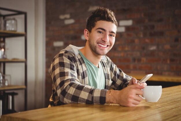 Souriant hipster boire du café et en utilisant un smartphone