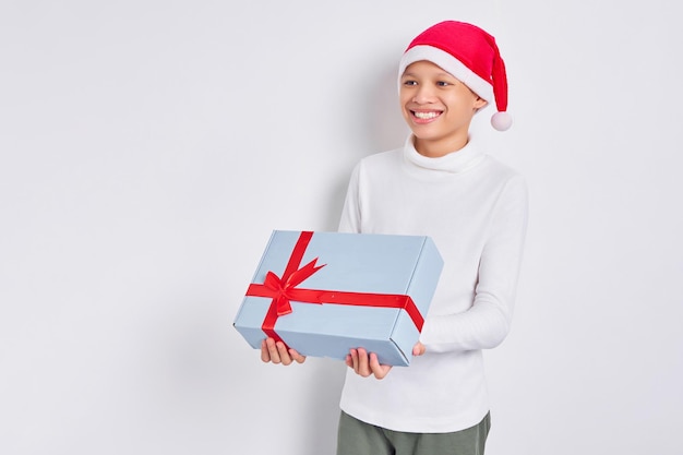 Souriant homme asiatique en chapeau de noël donnant une boîte-cadeau actuelle sur le côté gauche isolé sur fond blanc Homme recevant le cadeau du père noël