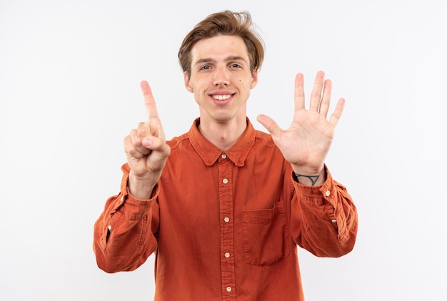 Souriant jeune beau mec vêtu d'une chemise rouge montrant différents numéros isolés sur mur blanc