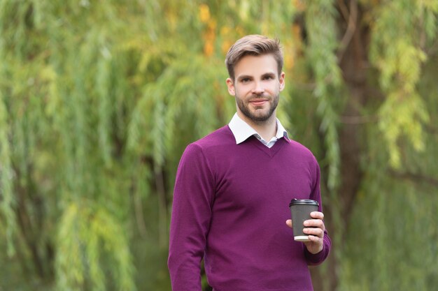 Souriant jeune bel homme boire le café du matin en plein air