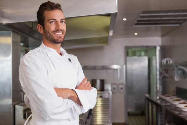 Souriant jeune chef debout avec les bras croisés