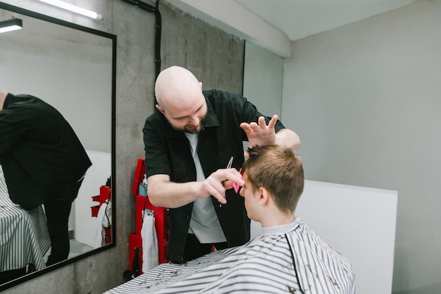 Souriant jeune coiffeur client se toilettant avec un peigne et des ciseaux