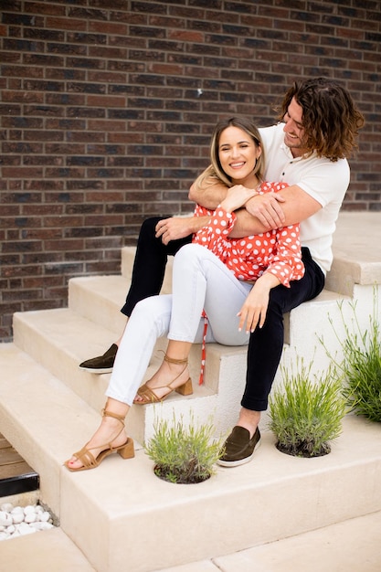 Souriant jeune couple amoureux devant le mur de briques de la maison