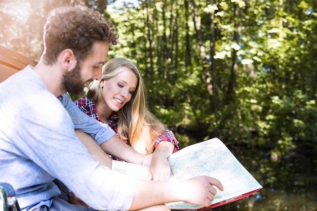 Souriant jeune couple lisant une carte à un ruisseau