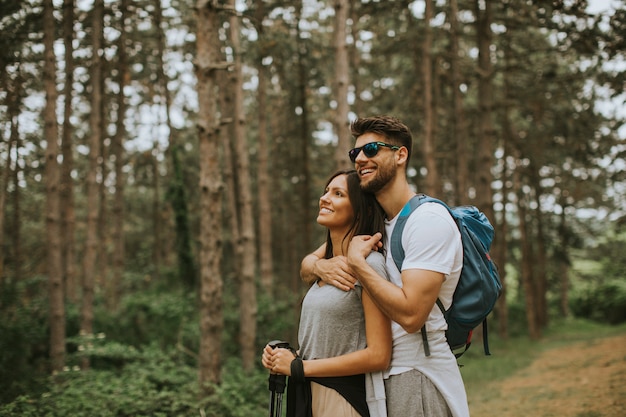 Souriant jeune couple marchant avec des sacs à dos dans la forêt