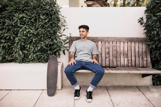 Souriant jeune garçon se détendre sur un banc