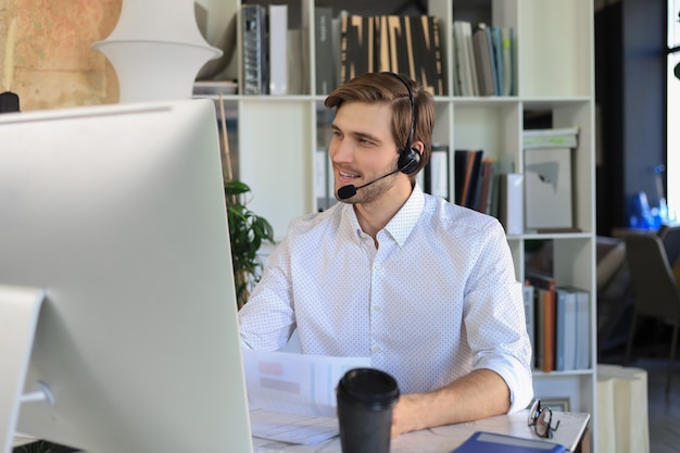 Souriant jeune homme d'affaires ayant un appel vidéo au bureau.