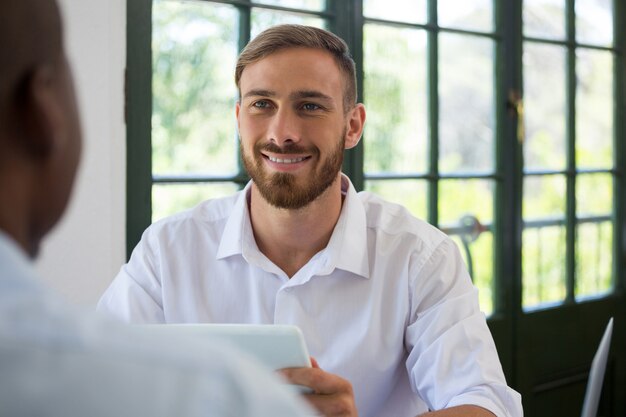 Souriant jeune homme d'affaires regardant collègue au restaurant