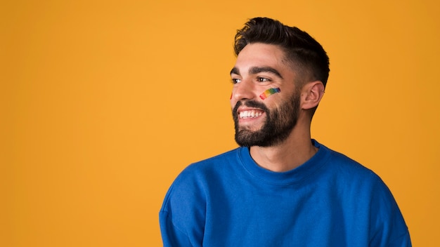 Photo souriant jeune homme avec arc-en-ciel lgbt sur le visage