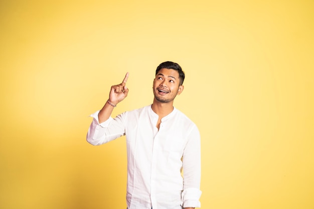 Souriant jeune homme asiatique avec le doigt pointé vers le haut