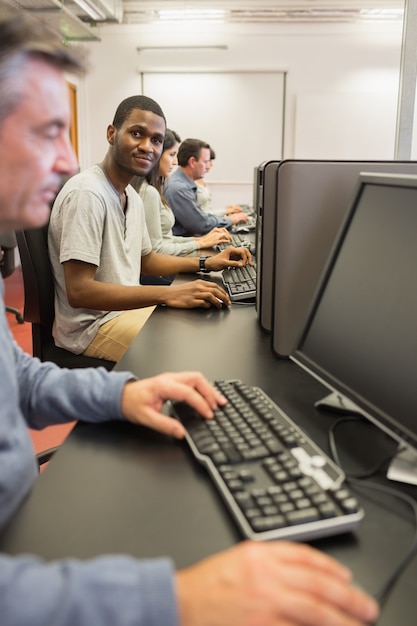 Souriant jeune homme au cours d&#39;informatique